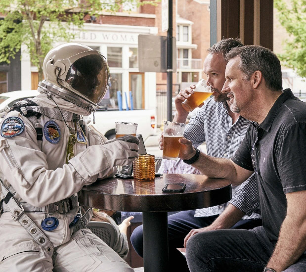 Astronaut having beer with business associates